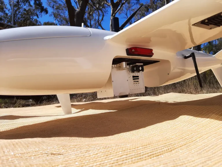 Fixed-wing drone with mounted LiDAR and photogrammetry sensors on launch mat in field environment